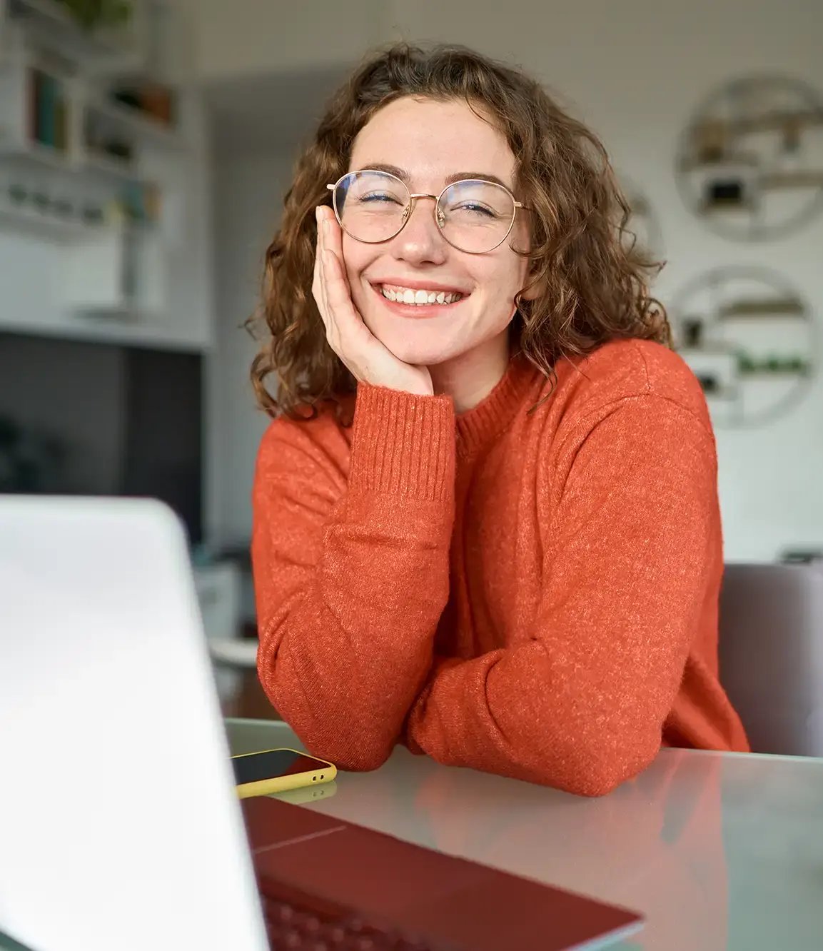 Woman in an orange sweater smiling at camera